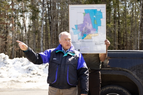 Man in front of map gesturing and speaking.