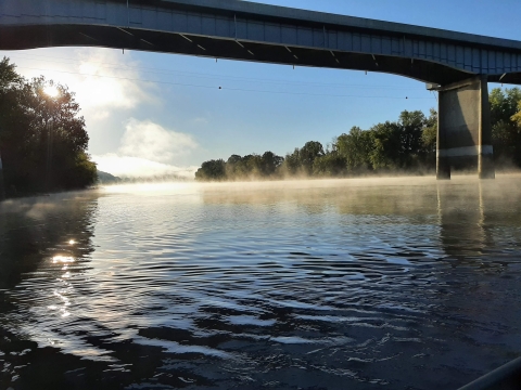A bridge spans a foggy river below