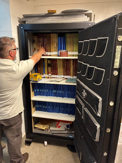 Quilcene National Fish Hatchery employee reaching for a historical fish culture records journal.