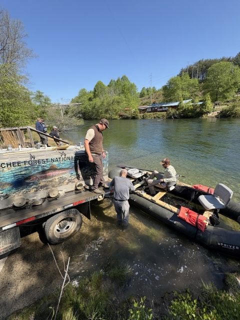 Service staff transfer trout from a stocking truck to a raft.