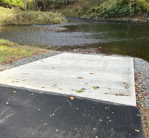 A gently sloping paved boat ramp leading to a river 