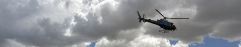 a helicopter hoovers in a cloudy sky