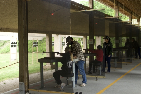 Youth in PPE aiming down a shooting area range. 