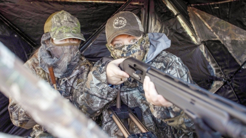 Two hunters in camouflage waiting in a hunting blind