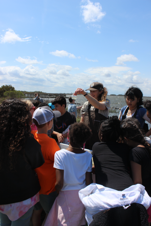 Refuge employee shows small container of water to young students.