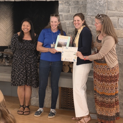 Refuge employees smile as one of them holds an award certificate.