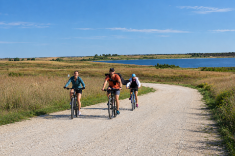 Three cyclists ride along the southern shore of Kirwin Reservoir