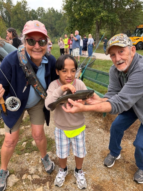 Child posing with volunteers holding fish