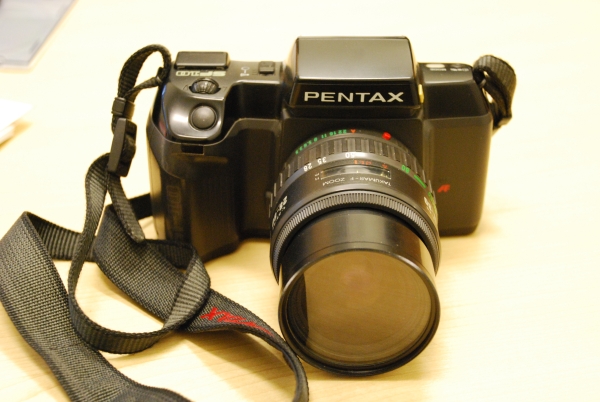A Pentax camera lies on a desk