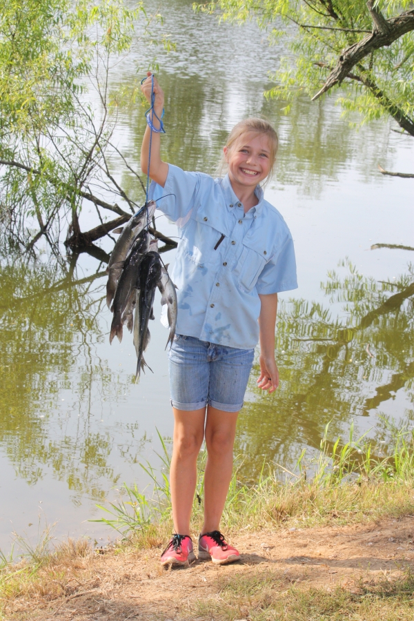 An image of a child holding up the fish they caught that day.