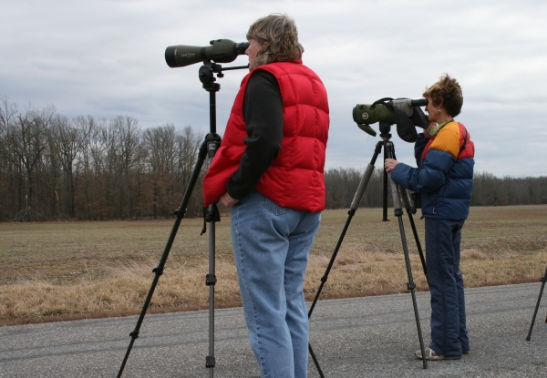 An image of two people looking through spotting scopes across a field.
