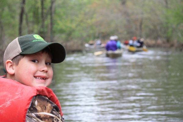 An image of a smiling child on a canoe trip.