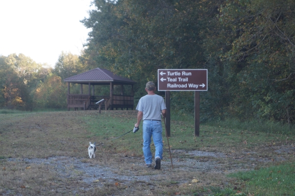 An image of a person walking their dog on a gravel trail.