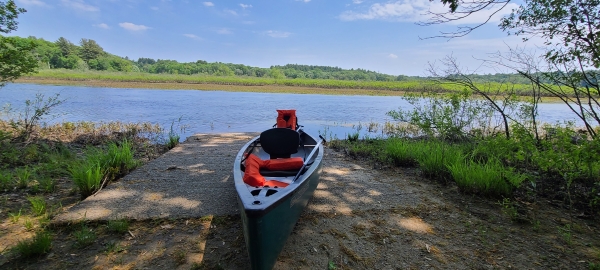 A canoe at the the canoe launch off of Weir Hill Trail, with the Sudbury River in the backgorund.