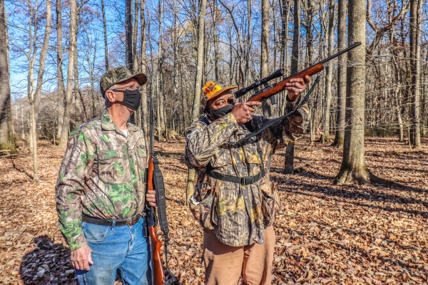 An image of two people in the woods hunting.