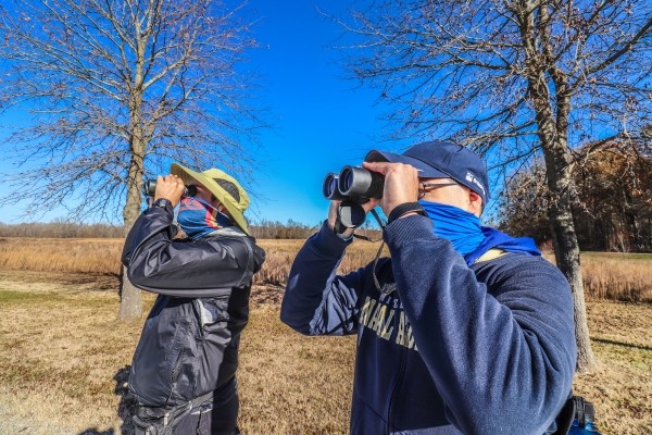 An image of two people birding with binoculars.