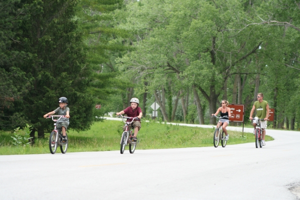 A family of four riding bikes on a refuge road during the summer.