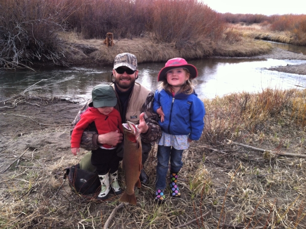 A fisherman poses with his children and a rainbow-cutthroat hybrid trout caught while fly fishing in Red Rock Creek