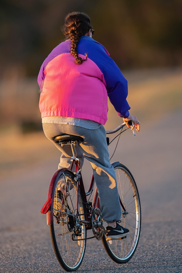 A person bicycling away from the photographer