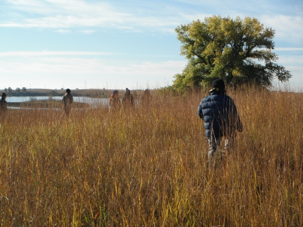 6 students hiking through tall prairie grasses in fall
