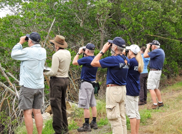 An image of a group of people holding binoculars looking in the same direction.