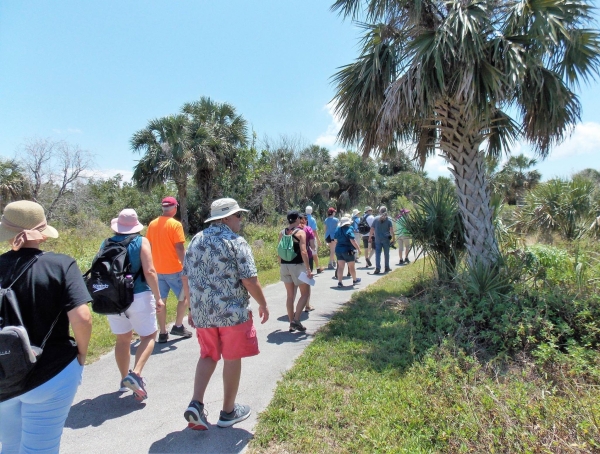 An image of people hiking on a paved trail on a sunny day.
