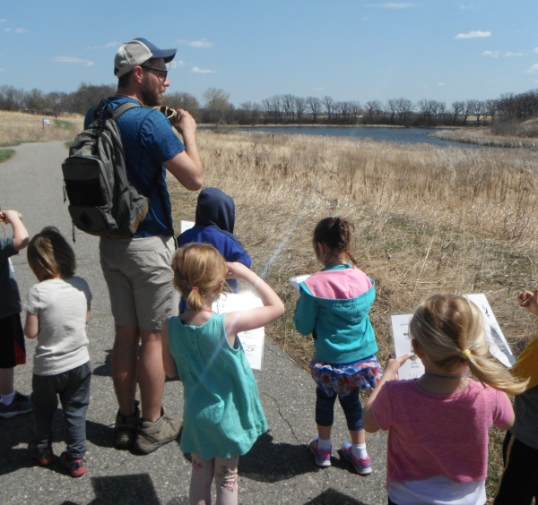 An adult leads several preschool children in bird watching