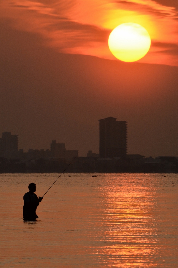 Fisherman wades out into Little Lagoon at sunset.