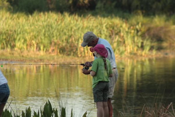 A child and grandfather bank fish in a freshwater pond