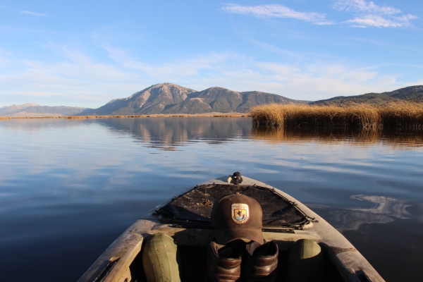 A Refuge staff member patrols Lower Red Rock Lake in a kayak with mountains in the background.