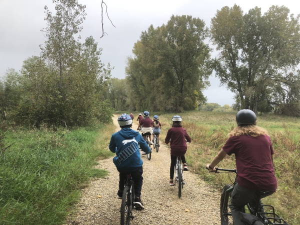 Youth biking on gravel path next to deciduous trees
