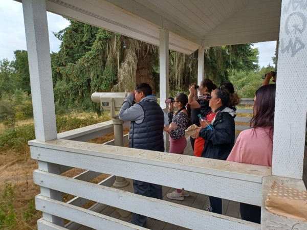 A family uses binoculars and the mounted spotting scope to look at birds.