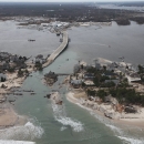 Aerial view of ocean breach surrounded by damaged beach front homes.