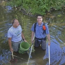 two men standing in a river