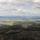 View of nearly the entire Refuge as seen from atop the summit of Baldy Mountain at 9863 feet; view includes Upper and Lower Lake, conifer forest, and a green valley floor with both lakes, wetlands and partly cloudy skies