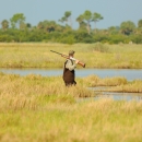A duck hunter wades through saltmarsh grasses
