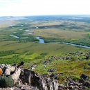 a person sitting on a hill looking down at a river valley