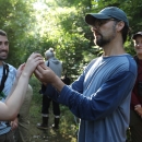Biologist holds a small songbird up for a group of onlooking students