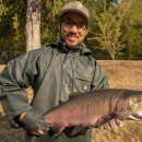Intern Eric Klingberg poses holding a adult coho salmon at the Quilcene National Fish Hatchery in Quilcene Washington.