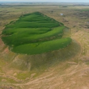 Crops of wheat growing on the top of a flood-carved mesa are a green contrast to the surrounding drier landscape.