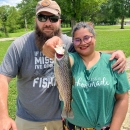 A couple posing with a Rainbow trout