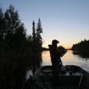 Silhouette of a person in a boat on a river at sunrise