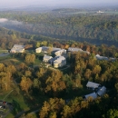 aerial image of campus with buildings, trees, and a river running in background