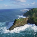 A lighthouse sits on a 180 foot high peninsula surrounded by the pacific ocean