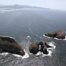 The Pacific Ocean crashes around the bases of three huge, arched, grassy islands 
