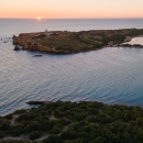 Aerial view of a beach with the sun setting in the background