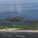 Aerial view of crescent shaped island with vegetation in middle ad sandy edges