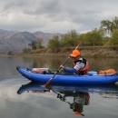 Person in a blue inflatable kayak on a calm river
