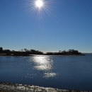 The sun in a crystal clear blue shy over a piece of land jutting into water