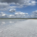 Floor bed covered with salt and water surrounded  by semi-covered cloud. 